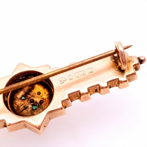 Pu&ograve; includere: Un fermaglio a forma di chiave in oro con un centro a forma di stella e pietre verdi. Il retro del fermaglio ha un marchio che recita "9 375 R".