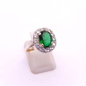 May include: A silver ring with a large oval green gemstone surrounded by smaller white gemstones.