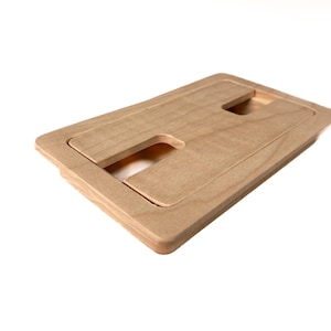 May include: A light wood rectangular cutout with two rectangular openings. The cutout is designed to be flush mounted in a surface.