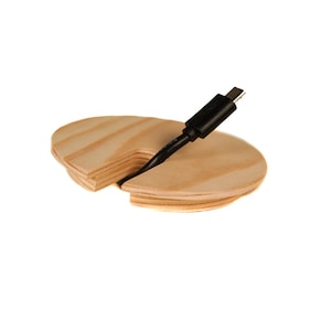 Puede incluir: Un organizador de cables de madera con un diseño dividido para sujetar un cable USB negro en su lugar.