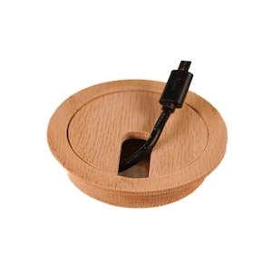 Op de afbeelding: Een ronde, houten kabeldoorvoer met een zwarte kabel die erdoorheen loopt. De doorvoer heeft een gladde, lichtbruine afwerking en een licht verhoogde rand.