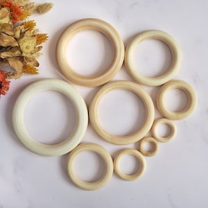 May include: A set of eight wooden rings in various sizes, ranging from small to large. The rings are all natural wood colour and have a smooth, polished finish.
