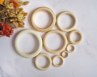 May include: A set of eight wooden rings in various sizes, ranging from small to large. The rings are all natural wood color and have a smooth, polished finish.