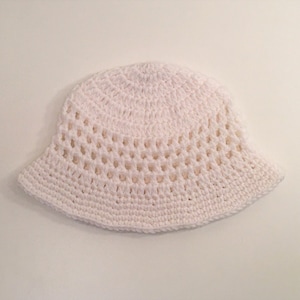 May include: A white crocheted bucket hat with a wide brim and an open weave pattern.