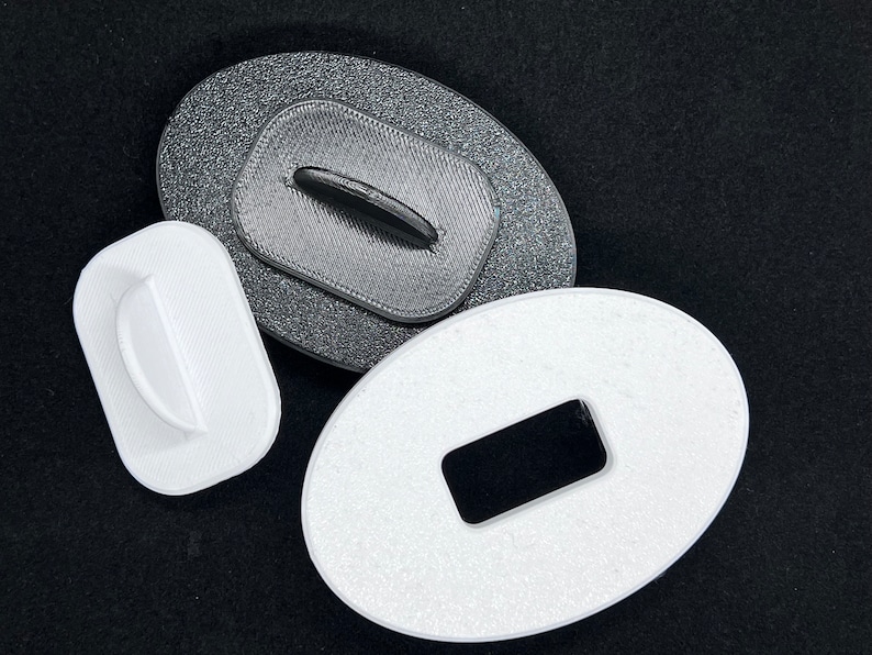 May include: Three oval-shaped plastic buttons with different sized holes in the center. The buttons are white and black.