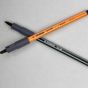 May include: Two black and gray Stabilo pens, one with a blue cap and the text "point 88 fine 0.4 Germany" and the other with a black cap and the text "Pen 68".
