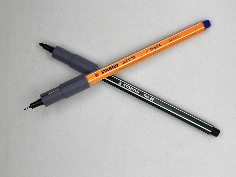 May include: Two black and gray Stabilo pens, one with a blue cap and the text "point 88 fine 0.4 Germany" and the other with a black cap and the text "Pen 68".
