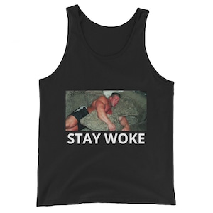 Puede incluir: Camiseta de tirantes negra con un gráfico blanco de un hombre durmiendo en un sofá con el texto "STAY WOKE" debajo.