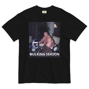 May include: Black t-shirt with a photo of a man eating a meal with the text "BULKING SEASON" printed below the photo.