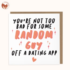 May include: A white card with black text that reads "You're not too bad for some random guy off a dating app." The text is in a playful, handwritten font. There is a small pink heart at the bottom of the card.
