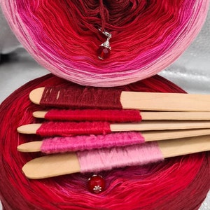 Può includere: Un gomitolo di filato ombré in tonalità di rosa, rosso e bordeaux. Il filato è avvolto a palla ed è pronto per essere utilizzato per la maglia o l'uncinetto.