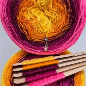 May include: A skein of yarn in a gradient of yellow, orange, pink, and purple. The yarn is wound around a cardboard tube and is ready to be used for knitting or crocheting.