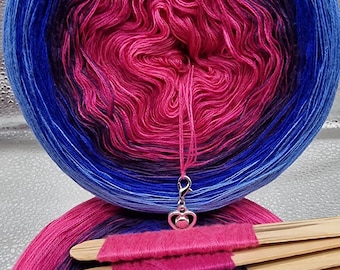 May include: A ball of ombre yarn in shades of pink, purple, and blue. The yarn is wound into a ball and is ready to be used for knitting or crocheting.