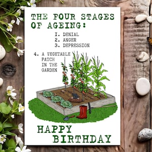 May include: A humorous birthday card with a green border and the text "The Four Stages of Ageing: 1. Denial 2. Anger 3. Depression 4. A Vegetable Patch in the Garden". The card features a cartoon illustration of a vegetable garden with a red rubber boot, a rake, and a shovel.
