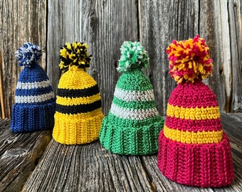 May include: Four crocheted hats in different colors and patterns. The hats are blue and white, yellow and black, green and white, and red and yellow.