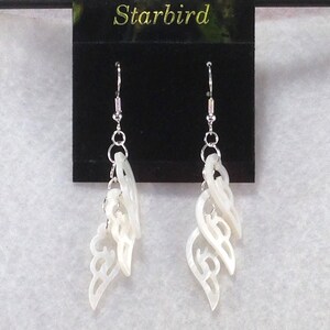 Puede incluir: Pendientes de concha blanca con un dise&ntilde;o delicado e intrincado. Los pendientes est&aacute;n hechos de m&uacute;ltiples capas de concha, cada una con una forma diferente. Los pendientes est&aacute;n suspendidos de ganchos de plata.