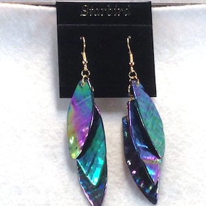 May include: A pair of iridescent dangle earrings with three layered leaf shapes. The earrings are gold-toned and have a Starbird brand tag.