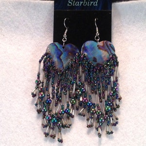 May include: A pair of iridescent heart-shaped earrings with a beaded fringe. The earrings are made of abalone shell and feature a silver hook.
