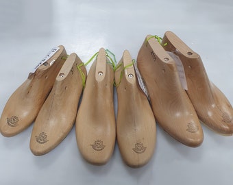 May include: Five wooden shoe lasts, used for shaping shoes, with different sizes marked on them. The lasts are light brown and have a smooth finish.