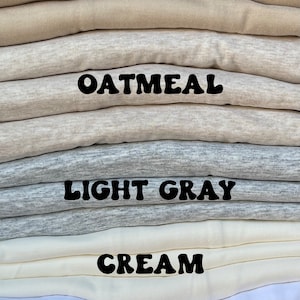 May include: A stack of folded fabric in five different colors: tan, oatmeal, light gray, cream, and white. The colors are labeled with black text.