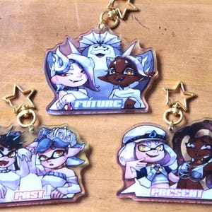 May include: Three clear acrylic keychains with colorful cartoon characters and text. The top keychain features three characters with the text "FUTURE". The middle keychain features two characters with the text "PAST". The bottom keychain features two characters with the text "PRESENT".