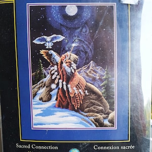 Puede incluir: Un kit de punto de cruz contado Dimensions The Gold Collection titulado Sacred Connection, de 28 cm x 41 cm. El diseño muestra a una persona con vestimenta tradicional y plumas, un paisaje nevado, un búho volando y un gran rostro de lobo.