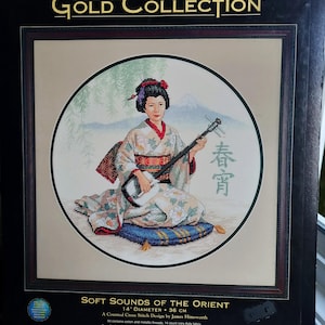 Puede incluir: Kit de punto de cruz contado The Gold Collection titulado Soft Sounds of the Orient de James Himsworth. El empaque presenta un diseño circular de una persona con kimono floral tocando el shamisen, con un fondo de montaña y texto.