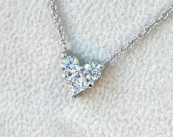 Puede incluir: Un collar de plata con un colgante en forma de corazón con tres pequeños diamantes.