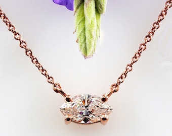 May include: A delicate rose gold chain necklace with a marquise-shaped diamond pendant.