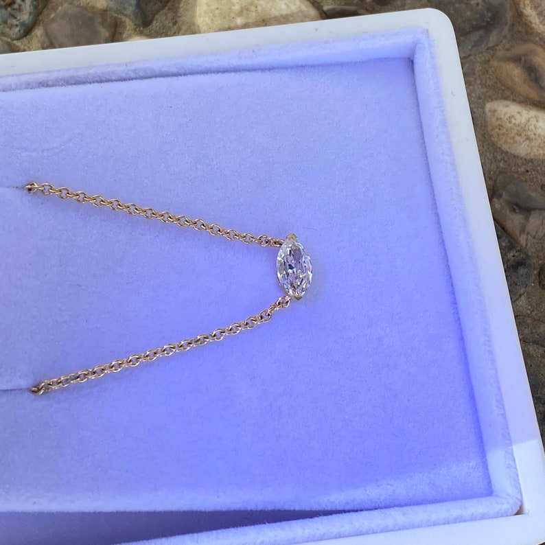 May include: A delicate gold chain necklace with a single oval-shaped diamond pendant.