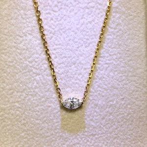 May include: A delicate gold chain necklace with a single, clear, oval-shaped diamond pendant.