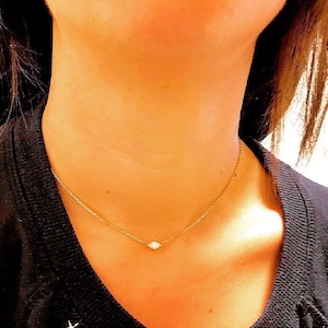 May include: A delicate gold chain necklace with a single, small, clear diamond pendant.
