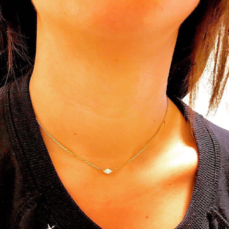 May include: A delicate gold chain necklace with a single, small, clear diamond pendant.