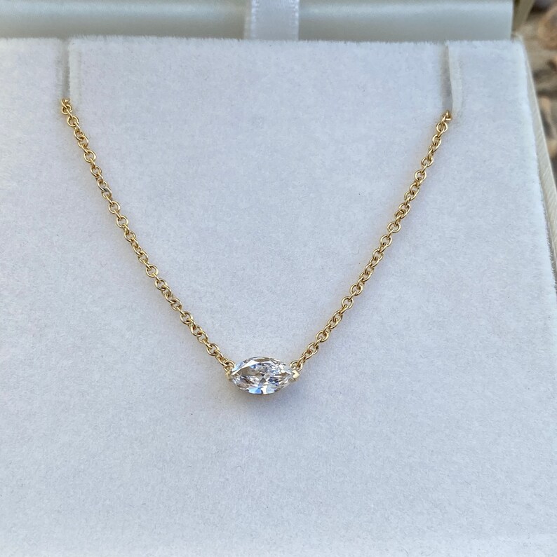 May include: A delicate gold chain necklace with a single marquise-shaped diamond pendant.