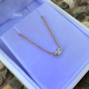 May include: A delicate gold chain necklace with a single marquise-shaped diamond pendant.