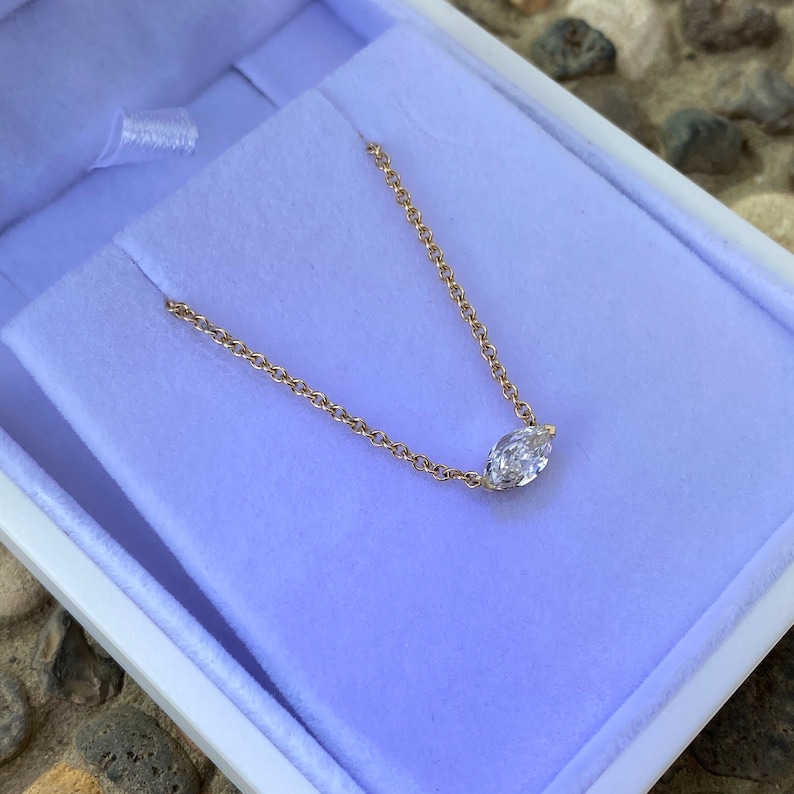 May include: A delicate gold chain necklace with a single marquise-shaped diamond pendant.