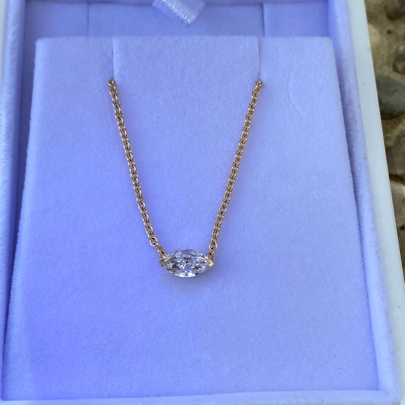 May include: A delicate gold chain necklace with a single marquise-shaped diamond pendant.