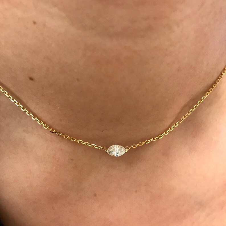 May include: A delicate gold chain necklace with a single, round, clear diamond pendant.