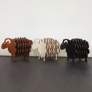 May include: Three wooden sheep coasters in brown, white and black. Each sheep is made of layered circles, creating a 3D effect.