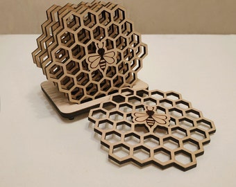 May include: Set of six wooden coasters featuring a honeycomb design with a bee silhouette in the centre. The coasters are stacked on a wooden base.