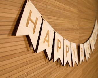 Könnte beinhalten: Ein Holzbanner mit den Worten "Happy Birthday" auf einer weißen Schnur vor einem Holzmaserungshintergrund.