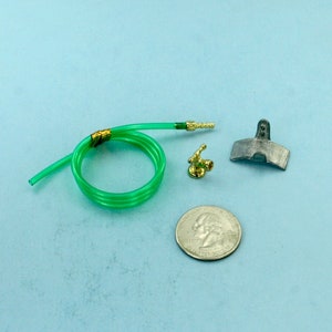 May include: A green garden hose, a gold metal sprinkler head, a silver metal garden tool, and a silver US quarter.