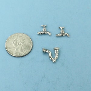 May include: Three miniature silver-toned faucets, two with spouts and one with a curved pipe, next to a US quarter for scale.