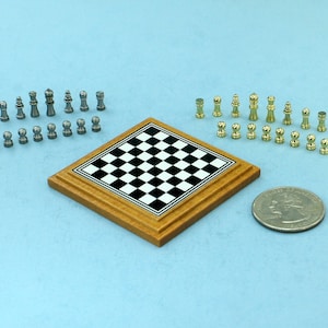 May include: A miniature chess set with a wooden board, black and white squares, and gold and silver chess pieces. The set is next to a US quarter for scale.