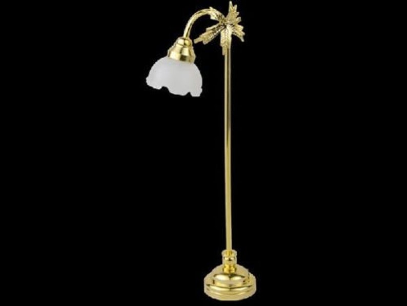 May include: A gold floor lamp with a white glass shade and a palm tree design. The lamp has a curved arm and a round base.
