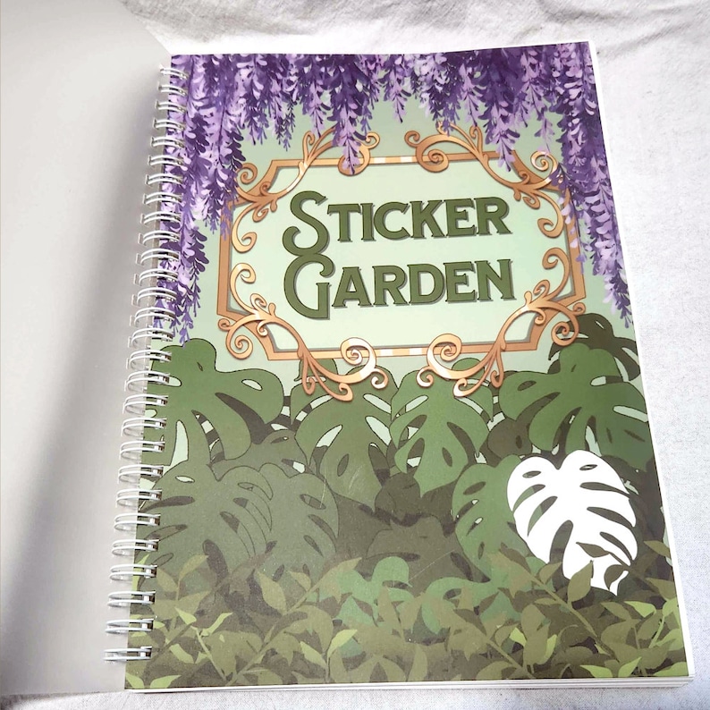 May include: A spiral bound sticker book with a green and gold cover featuring the text "Sticker Garden". The cover has a design of purple wisteria flowers hanging over a jungle scene with green leaves.