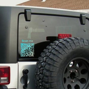 May include: A white Jeep with a black tire and a blue QR code sticker on the back window. The sticker says "Scan me".