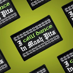 May include: Black and white embroidered patch with a green border. The patch says "I ceili dance in mosh pits".