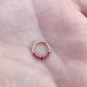 May include: Gold hoop earring with a row of pink gemstones.
