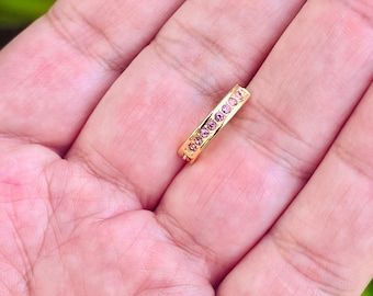 May include: A gold band ring with a row of pink gemstones.